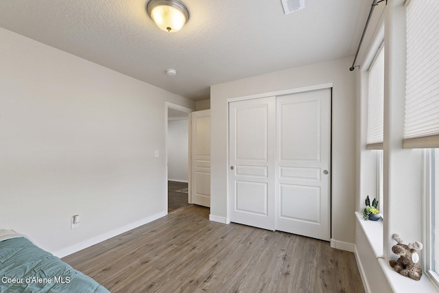 unfurnished bedroom featuring a textured ceiling, light hardwood / wood-style flooring, and a closet