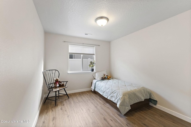 bedroom with hardwood / wood-style flooring and a textured ceiling