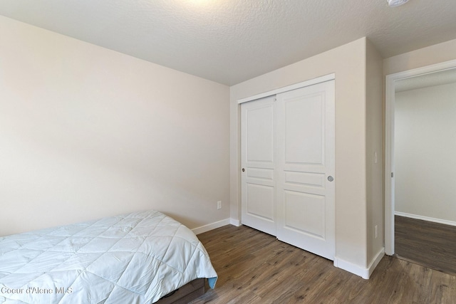 bedroom featuring dark hardwood / wood-style flooring, a textured ceiling, and a closet