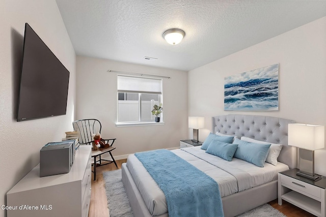 bedroom with light wood-type flooring and a textured ceiling