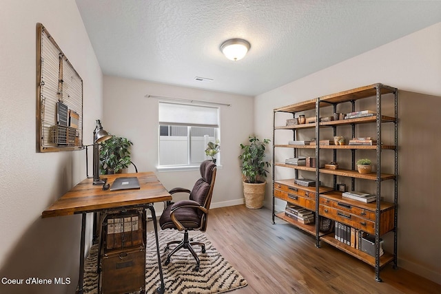 home office with wood-type flooring and a textured ceiling