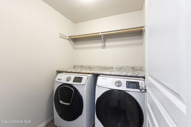 laundry area with washing machine and dryer and a textured ceiling