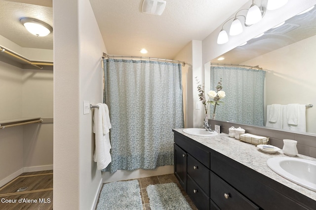 bathroom with a shower with shower curtain, vanity, and a textured ceiling