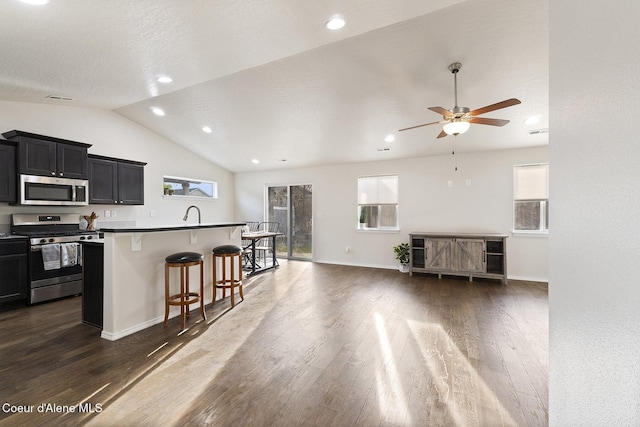 kitchen featuring a wealth of natural light, a kitchen island with sink, appliances with stainless steel finishes, and a breakfast bar area