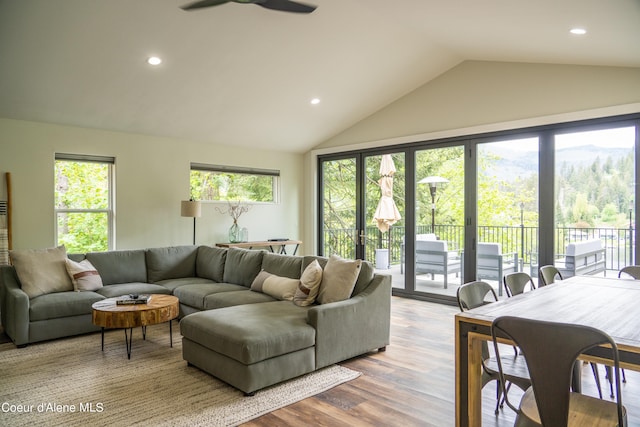 living room with ceiling fan, light hardwood / wood-style flooring, and vaulted ceiling