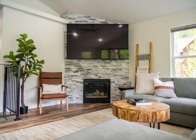 living room with hardwood / wood-style flooring, lofted ceiling, and a fireplace