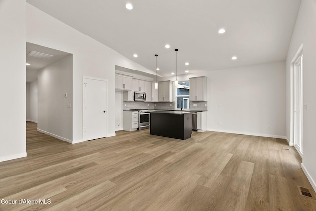 kitchen with vaulted ceiling, stainless steel appliances, hanging light fixtures, a center island, and tasteful backsplash