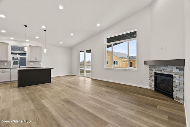 unfurnished living room featuring a fireplace, vaulted ceiling, and light hardwood / wood-style floors