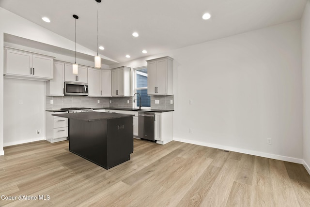 kitchen featuring sink, a center island, vaulted ceiling, pendant lighting, and appliances with stainless steel finishes