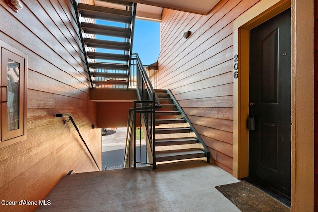 stairway featuring concrete floors and wood walls