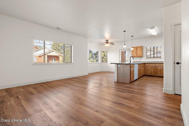 kitchen featuring white dishwasher, hardwood / wood-style floors, hanging light fixtures, and kitchen peninsula