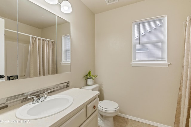 bathroom with tile patterned flooring, vanity, a healthy amount of sunlight, and toilet