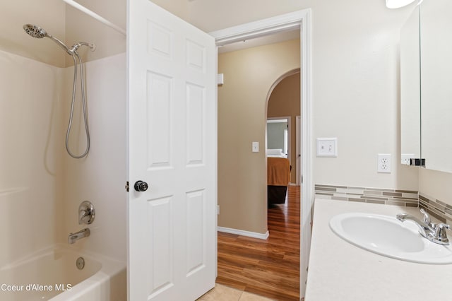 bathroom with hardwood / wood-style flooring, washtub / shower combination, and sink