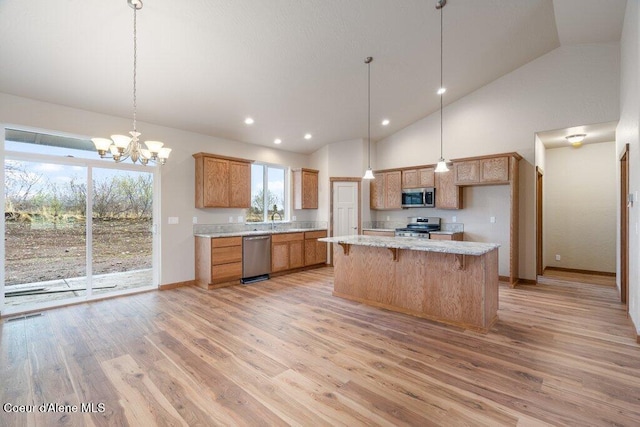 kitchen with stainless steel appliances, a center island, light hardwood / wood-style flooring, hanging light fixtures, and a chandelier