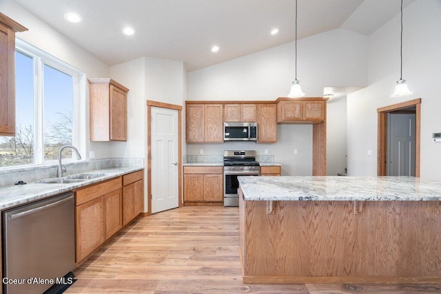 kitchen featuring decorative light fixtures, stainless steel appliances, light stone countertops, and sink