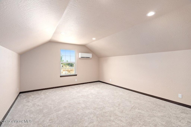 bonus room with an AC wall unit, a textured ceiling, vaulted ceiling, and light colored carpet