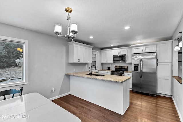 kitchen with white cabinets, dark wood-type flooring, stainless steel appliances, hanging light fixtures, and kitchen peninsula