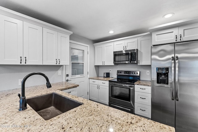 kitchen featuring light stone counters, sink, white cabinetry, and stainless steel appliances