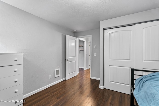 bedroom featuring a closet, dark hardwood / wood-style floors, and a textured ceiling