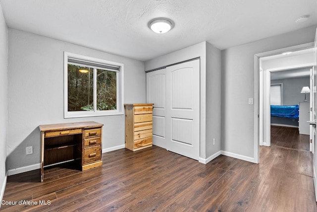 unfurnished bedroom featuring dark wood-type flooring, a textured ceiling, and a closet