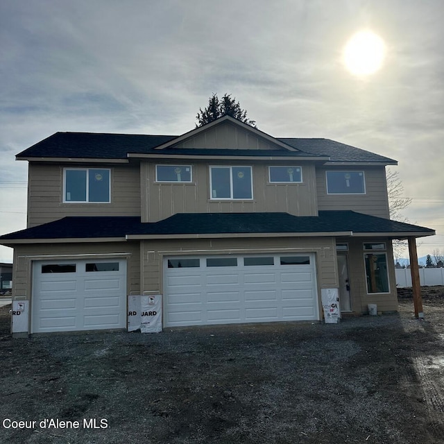 view of front of property featuring board and batten siding, an attached garage, and dirt driveway