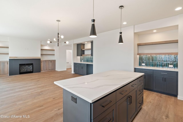 1605 N Garvin Ct, Spokane Valley, WA 99016 - kitchen with open shelves, light wood finished floors, a center island, gray cabinetry, and light stone countertops