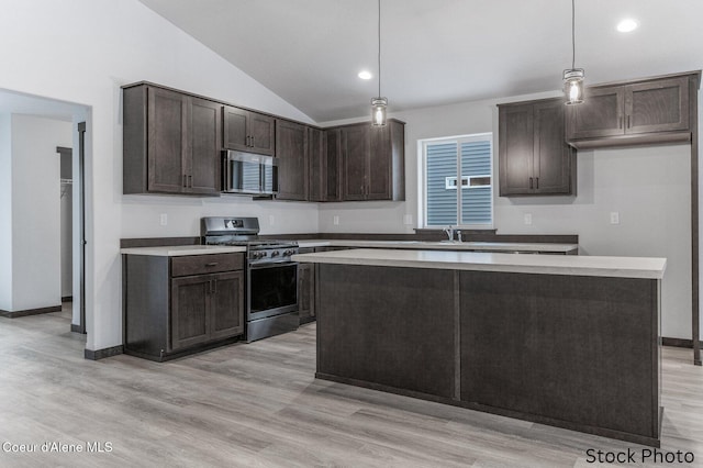 kitchen with decorative light fixtures, a center island, light hardwood / wood-style floors, dark brown cabinetry, and stainless steel appliances