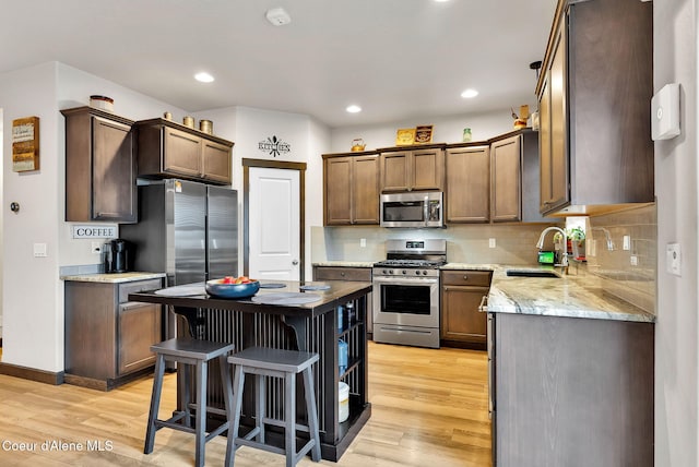 kitchen with recessed lighting, a sink, stainless steel appliances, light wood-style floors, and backsplash