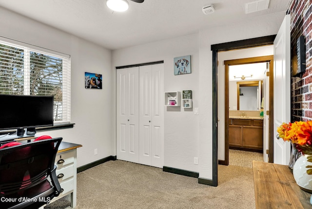 office area with a sink, light colored carpet, visible vents, and baseboards