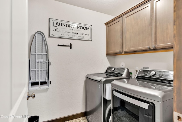 laundry area featuring cabinet space, washing machine and dryer, baseboards, and a textured wall