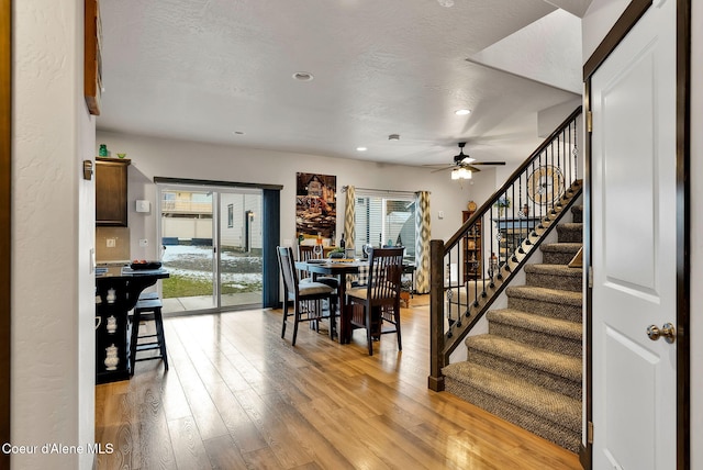 dining space featuring light wood-type flooring, a textured ceiling, a ceiling fan, and stairway