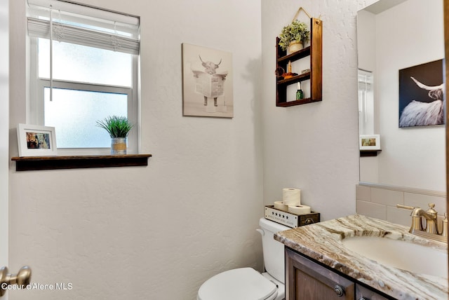 bathroom with tasteful backsplash, toilet, and vanity