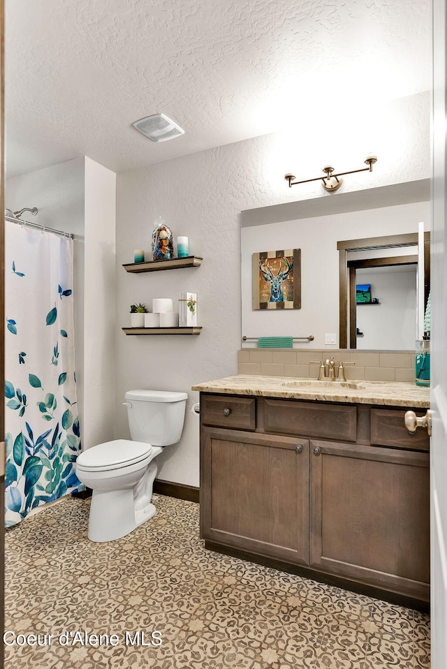 bathroom with visible vents, toilet, vanity, a textured wall, and a textured ceiling