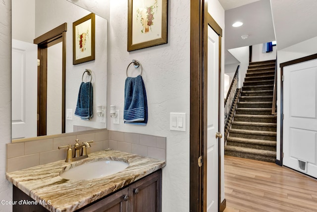 bathroom with wood finished floors, vanity, and a textured wall