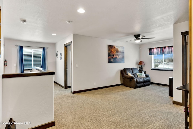 living area with baseboards, light colored carpet, and a textured ceiling