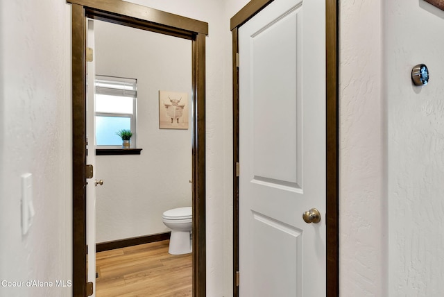 bathroom with toilet, wood finished floors, and baseboards