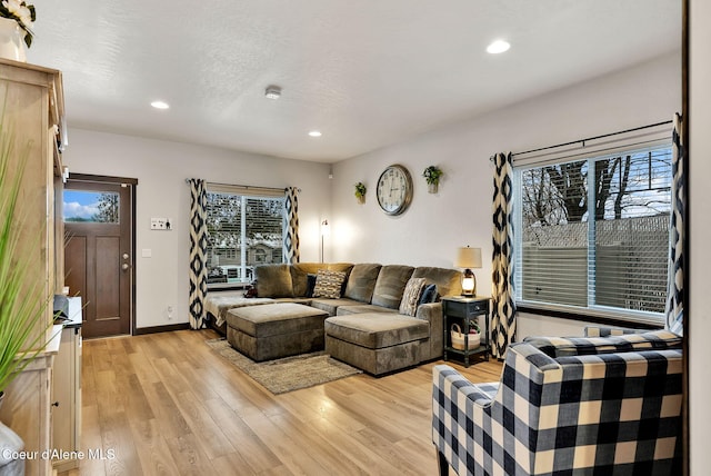 living area with recessed lighting, light wood finished floors, and a textured ceiling