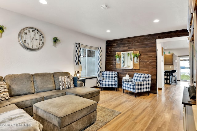 living area with recessed lighting, light wood-style floors, wooden walls, and an accent wall