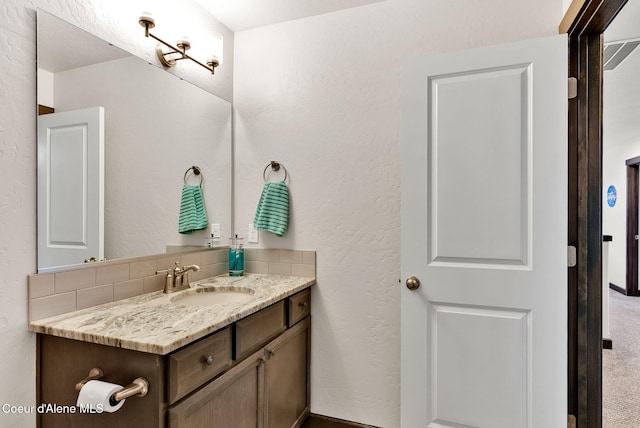 bathroom with vanity and a textured wall