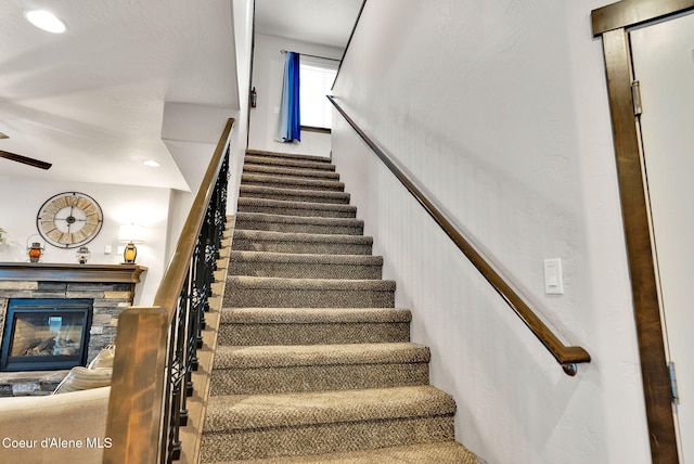 stairway featuring ceiling fan, recessed lighting, a fireplace, and wainscoting