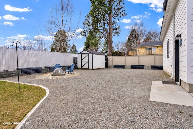 view of yard with an outbuilding, a shed, an outdoor fire pit, and a fenced backyard