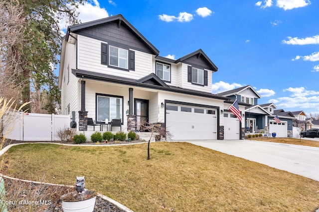 view of front of home with driveway, a front lawn, fence, covered porch, and an attached garage