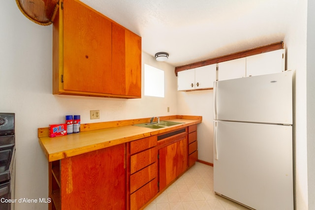 kitchen featuring white cabinetry, sink, and white fridge