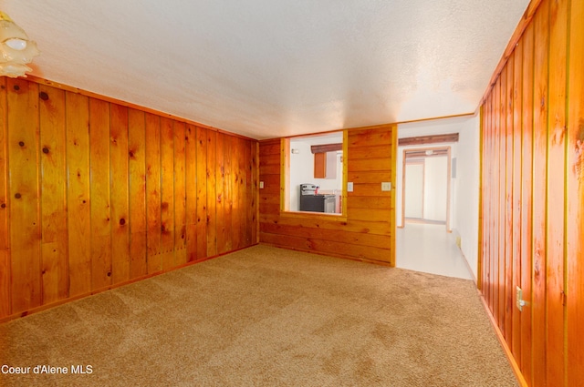 carpeted empty room with ornamental molding, a textured ceiling, and wooden walls