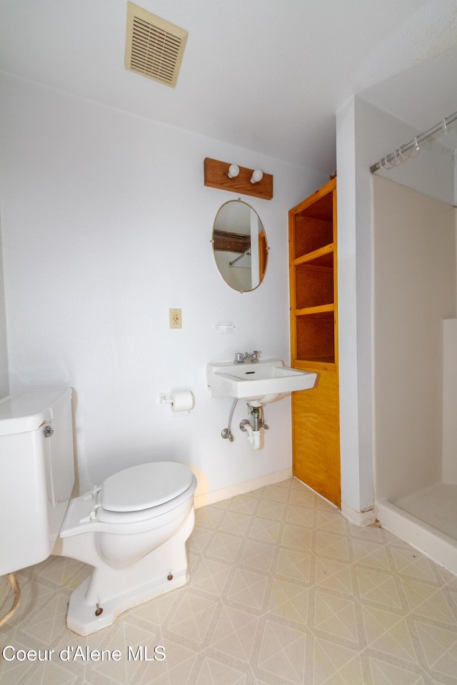 bathroom with walk in shower, sink, and toilet