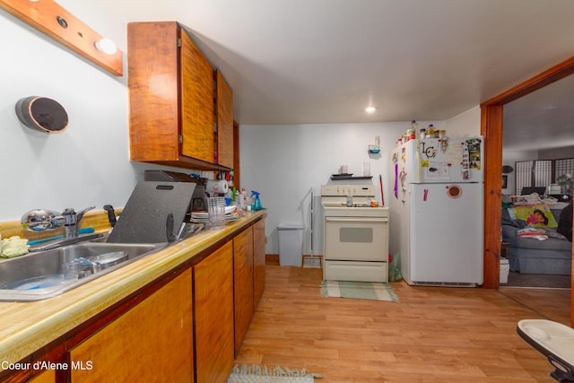 kitchen with white appliances, sink, and light hardwood / wood-style flooring