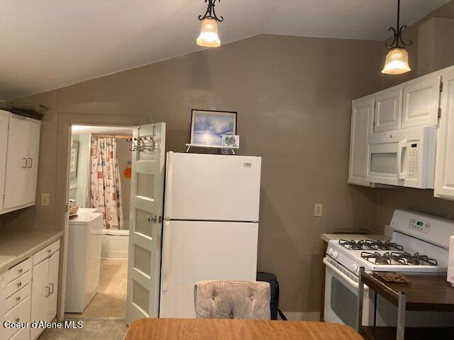 kitchen featuring white appliances, washer / clothes dryer, vaulted ceiling, hanging light fixtures, and white cabinetry