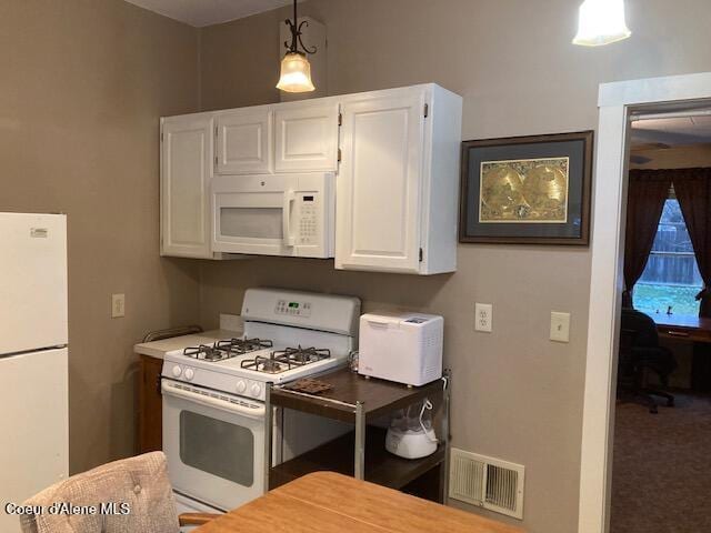 kitchen with white appliances, decorative light fixtures, and white cabinetry