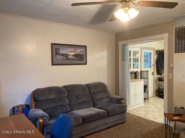 living room featuring ceiling fan, crown molding, and carpet flooring