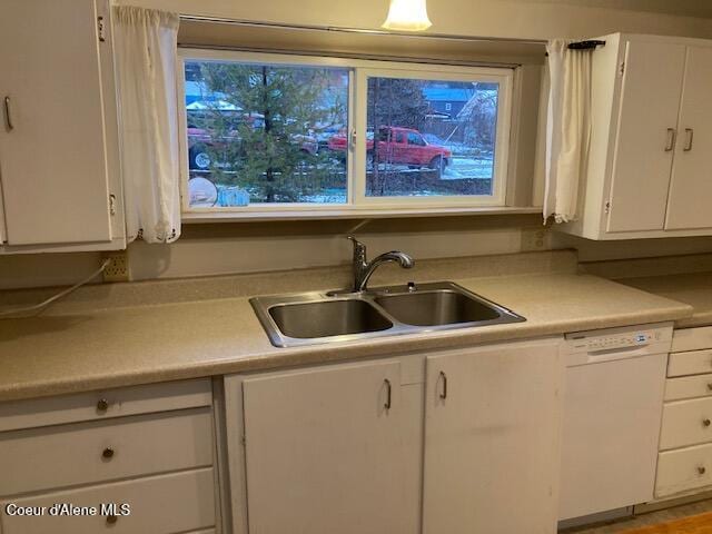 kitchen featuring white dishwasher, white cabinets, and sink